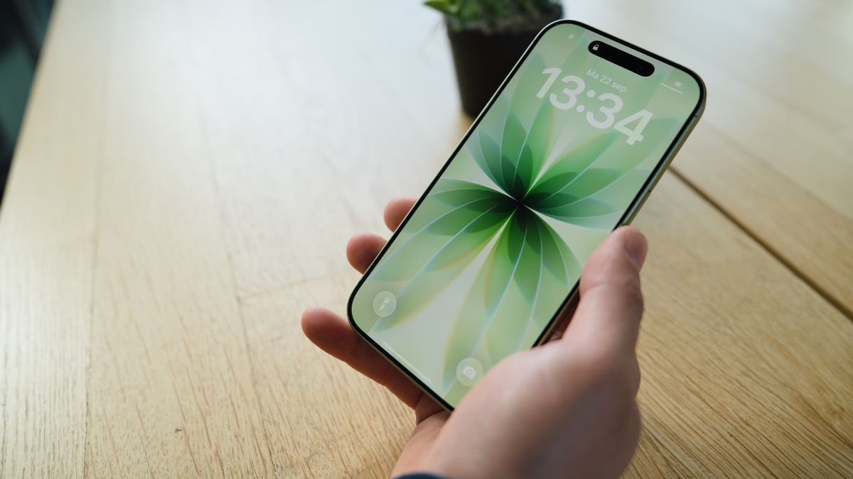 Persoon houdt iPhone 17 met saliegroen vergrendelscherm vast