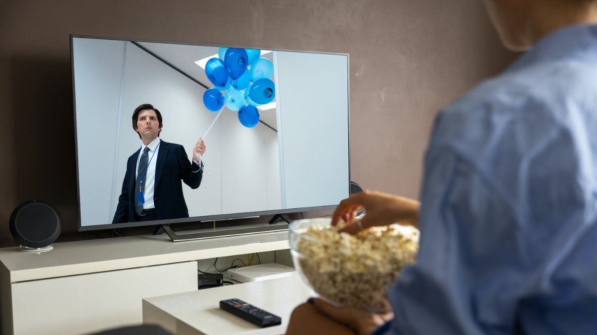 Man op bank met popcorn en Severance op televisie