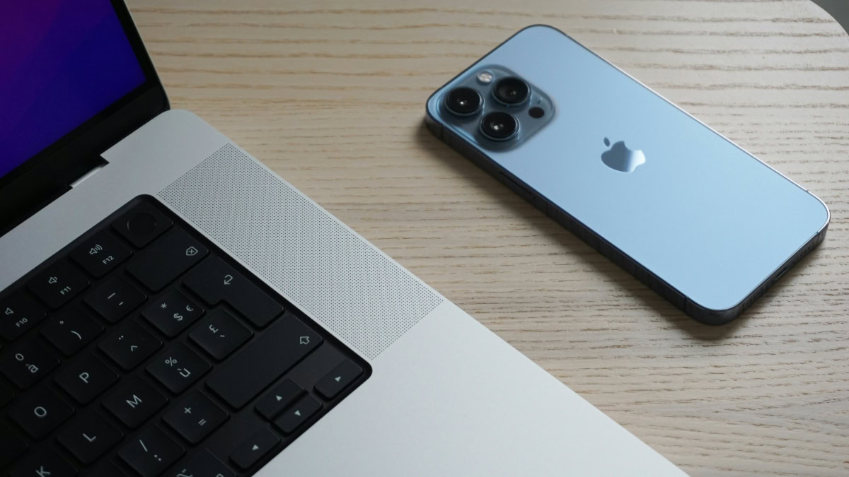 iPhone en MacBook naast elkaar op houten ondergrond
