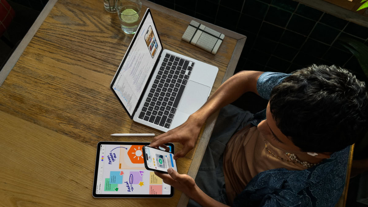 Persoon aan bureau met MacBook, iPad en iPhone